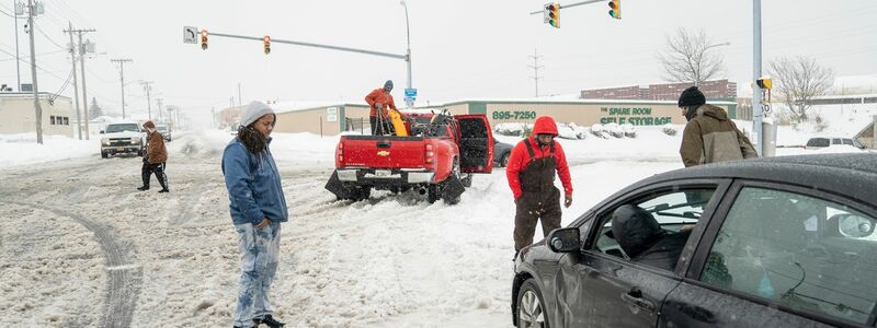 Anwohner helfen einem im Schnee steckengebliebenen Autofahrer in Buffalo. - Foto: Libby March/The Buffalo News/AP/dpa