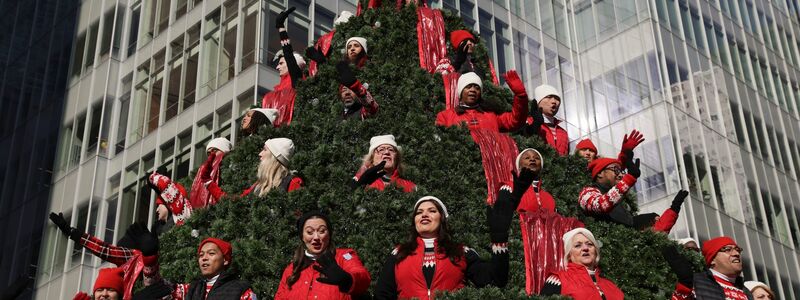 Darsteller auf dem Macy's Singing Christmas Tree-Wagen winken den Zuschauern während der Macy's Thanksgiving Day Parade zu. - Foto: Jeenah Moon/AP/dpa