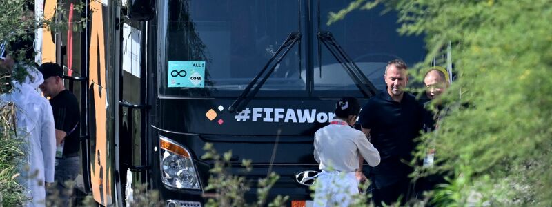 Hansi Flick (2.v.r.) steht bei der Abreise des DFB-Teams vor dem Mannschaftsbus. - Foto: Federico Gambarini/dpa
