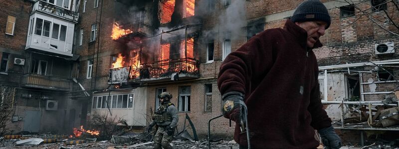 Ein Anwohner verlässt sein Wohnhaus in Bachmut, das nach einem Beschuss in Flammen steht. - Foto: Libkos/AP/dpa