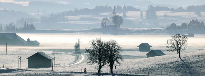Das mit Neuschnee bedeckte und im Morgendunst liegende Voralpenland. - Foto: Karl-Josef Hildenbrand/dpa