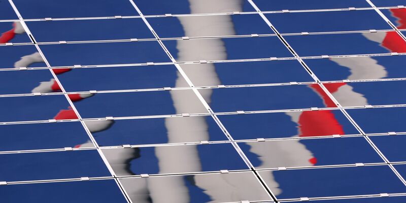 Ein Windrad spiegelt sich in einer Solar-Anlage. - Foto: Karl-Josef Hildenbrand/dpa