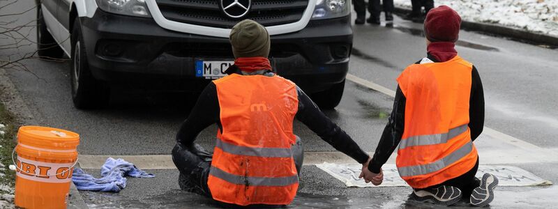 Zwei Klimaaktivisten während einer Protestaktion der Gruppe Letzte Generation in München. - Foto: Peter Kneffel/dpa