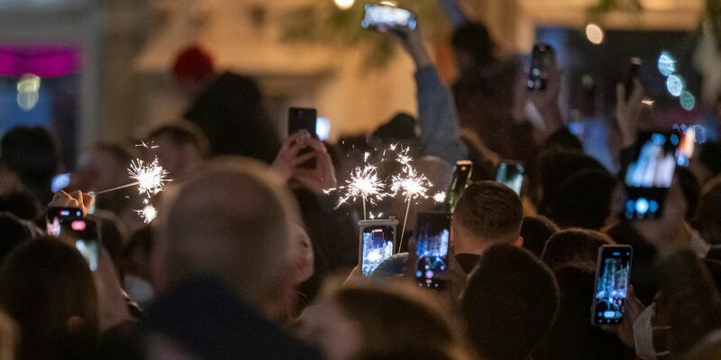 Menschen machen Fotos mit ihren Smartphones, während sie den Jahreswechsel feiern. - Foto: Peter Kneffel/dpa