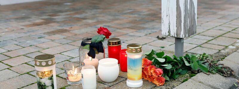 Anwohner haben neben einem abgelegten Blumenstrauß Kerzen vor dem Haus aufgestellt, wo am Freitag eine 14 Jahre alte Jugendliche bei einer Gewalttat getötet wurde. - Foto: Daniel Löb/dpa