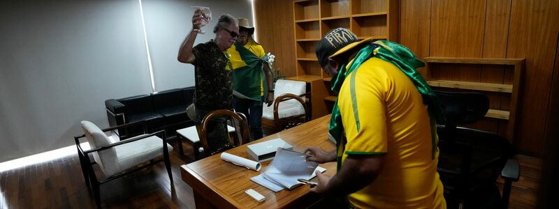 Bolsonaro-Anhänger wühlen sich in einem Büro des Palacio do Planalto, dem offiziellen Sitz des brasilianischen Präsidenten, durch Papiere. - Foto: Eraldo Peres/AP/dpa
