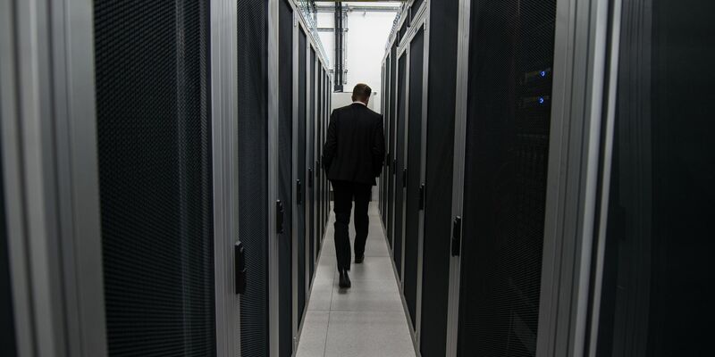 Ein Mitarbeiter der Firma DE-CIX geht zwischen Server-Schränken hindurch. - Foto: Andreas Arnold/dpa