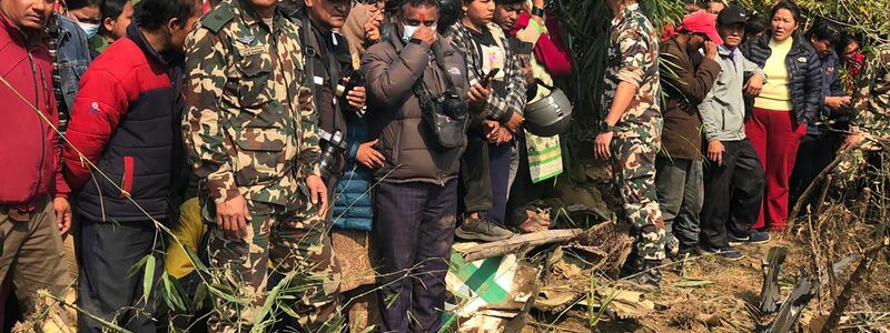 Einheimische betrachten das Wrack des abgestürzten Passagierflugzeugs in Pokhara. - Foto: AP/dpa