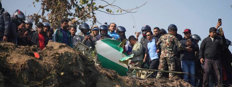 Einheimische und Rettungskräfte in Pokhara in der Nähe des Wracks des abgestürzten Passagierflugzeugs. - Foto: Yunish Gurung/AP/dpa