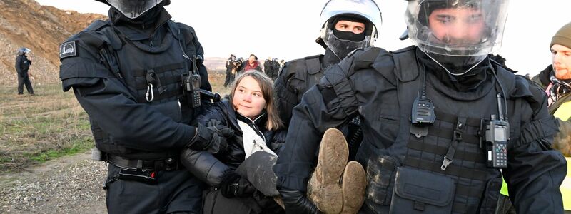 Polizisten tragen die schwedische Klimaaktivistin Greta Thunberg aus einer Gruppe von Demonstranten und Aktivisten heraus vom Rand des Braunkohlentagebaus Garzweiler II weg. - Foto: Roberto Pfeil/dpa