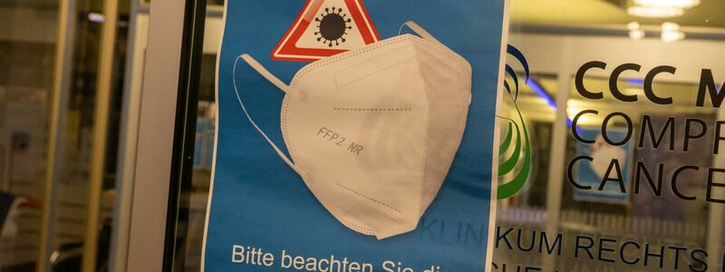 Ein Plakat mit der Aufschrift „Bitte beachten Sie die FFP2-Maskenpflicht“ hängt am Eingang des Krankenhaus „Rechts der Isar“. - Foto: Peter Kneffel/dpa