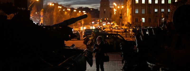 Eine Frau betrachtet zerstörte russische Panzer in Kiew. - Foto: Daniel Cole/AP/dpa