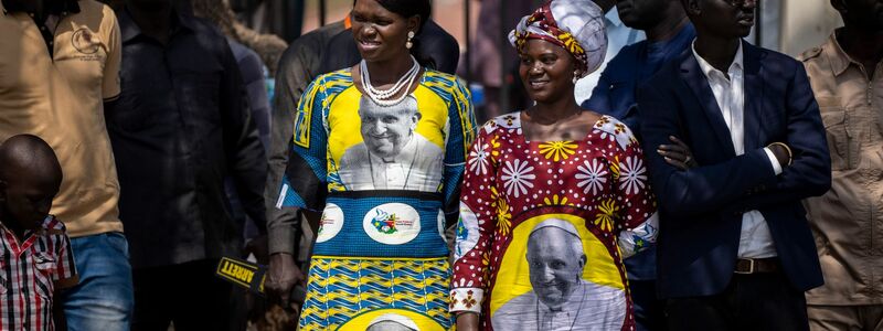 Gefeiert wie ein Popstar: Zwei Frauen tragen Kleider, auf denen ein Foto von Papst Franziskus zu sehen ist. - Foto: Ben Curtis/AP/dpa