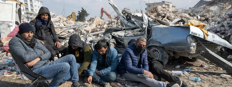 Junge Helfer sitzen in Antakya erschöpft zwischen den Trümmern. - Foto: Boris Roessler/dpa