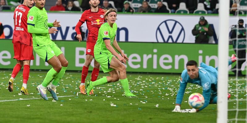Kaum zu stoppen: Leipzigs Torschütze Johan Bakayoko (r) wird von den Wolfsburgern Joakim Maehle und Mohammed Amoura bedrängt. - Foto: Swen Pförtner/dpa