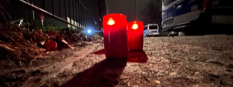 Brennende Kerzen stehen an einem Park in Pankow neben Polizeifahrzeugen. Nach dem Tod des Mädchens legten Menschen in der Nähe des Fundortes auch eine gelbe Blume und ein kleines Kuscheltier ab. - Foto: Paul Zinken/dpa