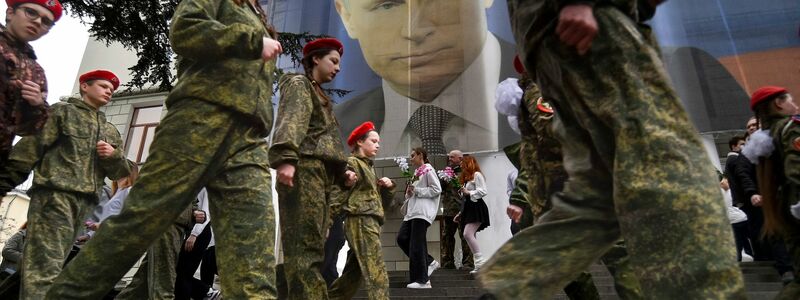 Uniformierte Jugendliche marschieren in Jalta anlässlich einer Aktion zum neunten Jahrestag der Krim-Annexion an einem Bild des russischen Präsidenten Wladimir Putin vorbei. - Foto: Uncredited/AP/dpa