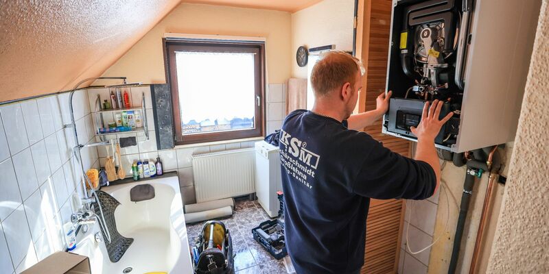 Ein Mitarbeiter einer Sanitär- und Heizungsbaufirma installiert eine moderne Gasbrennwerttherme in einem Einfamilienhaus. - Foto: Jan Woitas/dpa