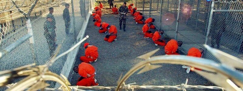 Ein von der US-Armee herausgegebenes Foto aus dem Jahr 2002 zeigt in orangefarbene Overalls gekleidete Häftlinge, die im Camp X-Ray auf dem Boden knien. - Foto: Shane T. McCoy/epa/dpa