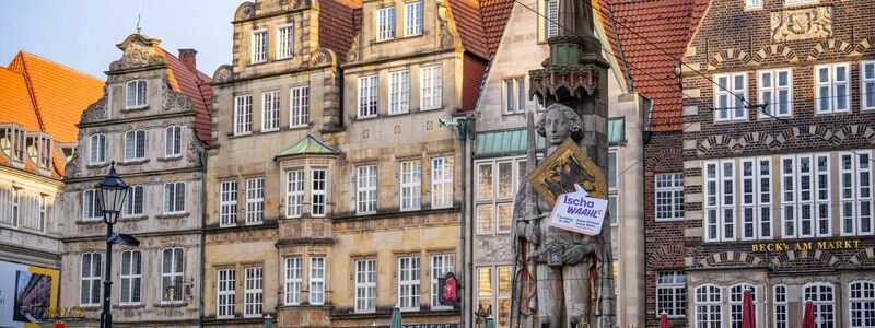 Ein Schild mit der Aufschrift «Ischa Waahl» hängt am Schild des Roland von Bremen auf dem Platz vor dem Rathaus. - Foto: Sina Schuldt/dpa