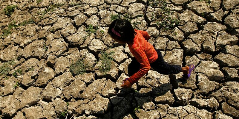 Ein philippinisches Kind läuft in der Provinz Cavite durch einen ausgetrockneten Bewässerungskanal. - Foto: Francis R. Malasig/EPA/dpa