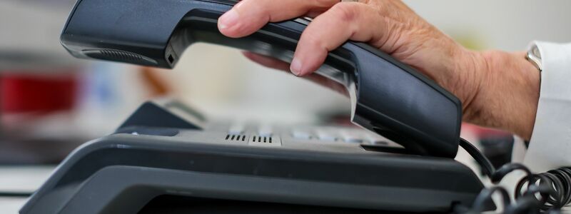 Eine Frau nimmt einen Telefonhörer in die Hand. - Foto: Jan Woitas/dpa