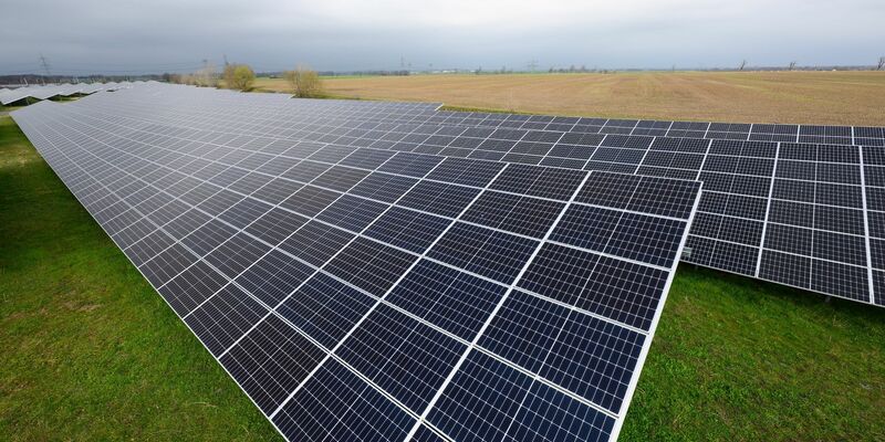 Solaranlagen sind für ein Photovoltaik-Speicher-Kraftwerk auf einer Wiese montiert. - Foto: Robert Michael/dpa