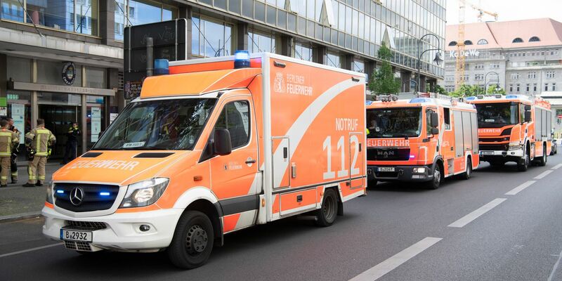 Einsatzfahrzeuge der Feuerwehr stehen vor dem mehrgeschossigen Gebäude, in dem es zu einem tödlichen Unfall mit einem Paternoster gekommen war. - Foto: Paul Zinken/dpa