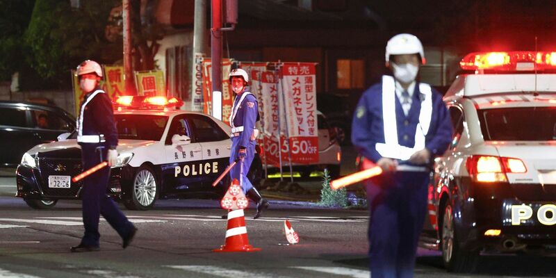 Polizisten stehen Wache auf einer Straße in der Nähe eines Gebäudes, in dem sich ein Mann verschanzt hat. - Foto: Takuto Kaneko/Kyodo News/AP/dpa