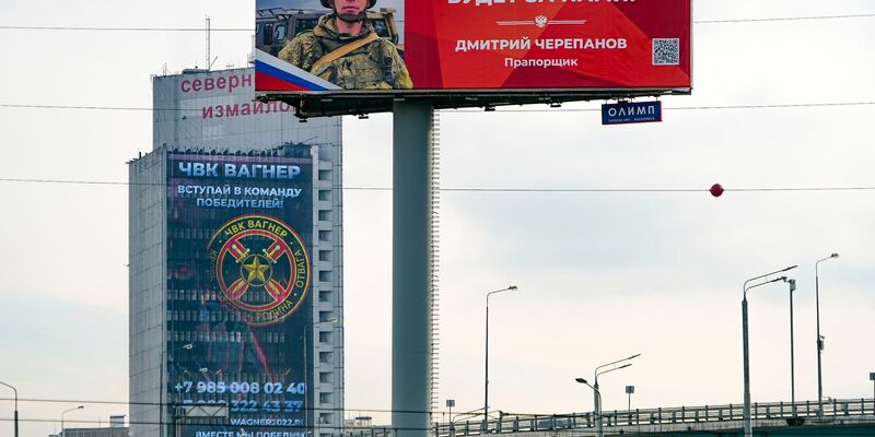 Ein Werbeschild, auf dem für das Militärunternehmen Wagner (hinten) geworben wird und auf dem zu lesen ist «Schließen Sie sich dem Team der Sieger an». - Foto: Alexander Zemlianichenko/AP/dpa