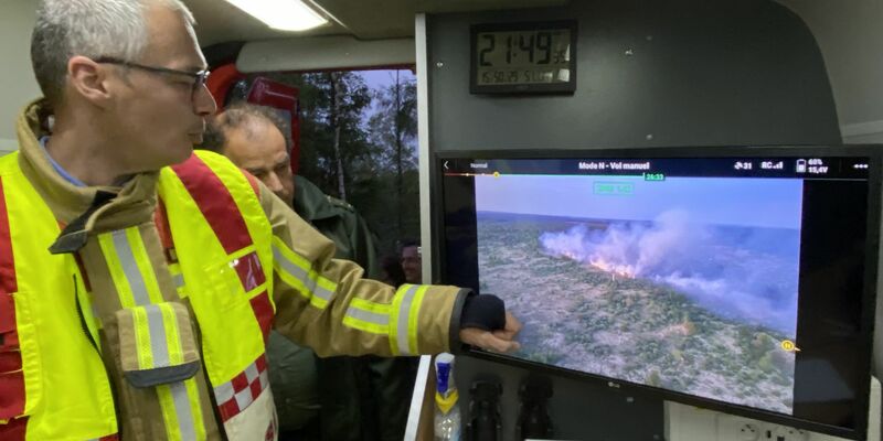 Der Feuerwehrkommandant Francis Cloth (l) zeigt den Moorbrand auf einem Bildschirm. - Foto: Francoise Peiffer/Belga/dpa