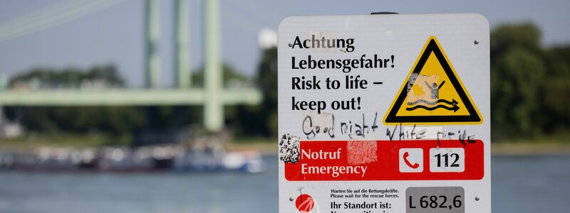 Ein Schild am Rheinufer weist auf die Gefahren beim Schwimmen im Fluss hin. - Foto: Rolf Vennenbernd/dpa