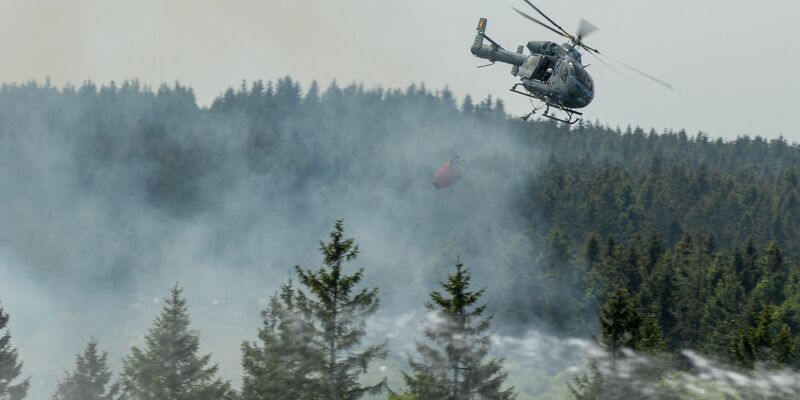 Die Feuerwehr versucht mit einem Hubschrauber einen Moorbrand im deutsch-belgischen Grenzgebiet bei Aachen zu löschen. - Foto: Ralf Roeger/dmp-press/dpa