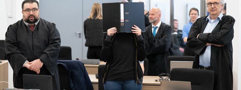 Die Angeklagte (M) steht bei der Fortsetzung des Prozesses im OLG Dresden im Verhandlungssaal. - Foto: Sebastian Kahnert/dpa