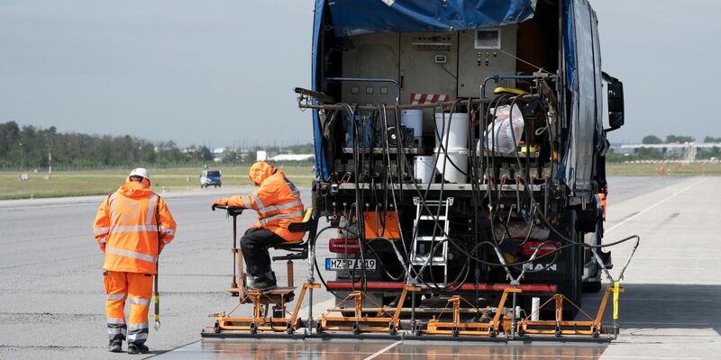 Eine spezielle Flüssig-Grundierung bringen Arbeiter mit einem Spezialfahrzeug auf der Landebahn Nordwest auf dem Flughafen in Frankfurt an. Am Frankfurter Flughafen hat der Betreiber Fraport die frisch sanierte Landebahn Nordwest nach wenigen Betriebsstunden wieder gesperrt. - Foto: Boris Roessler/dpa