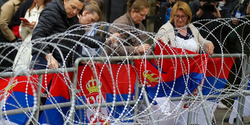 Frauen befestigen serbische Flaggen an einem Zaun vor dem Rathaus während einer Demonstration in der Stadt Zvecan im Norden des Kosovo. - Foto: Bojan Slavkovic/AP
