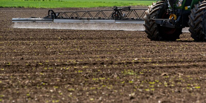 Ein Traktor bringt auf einem Acker Pflanzenschutzmittel aus. - Foto: Armin Weigel/dpa