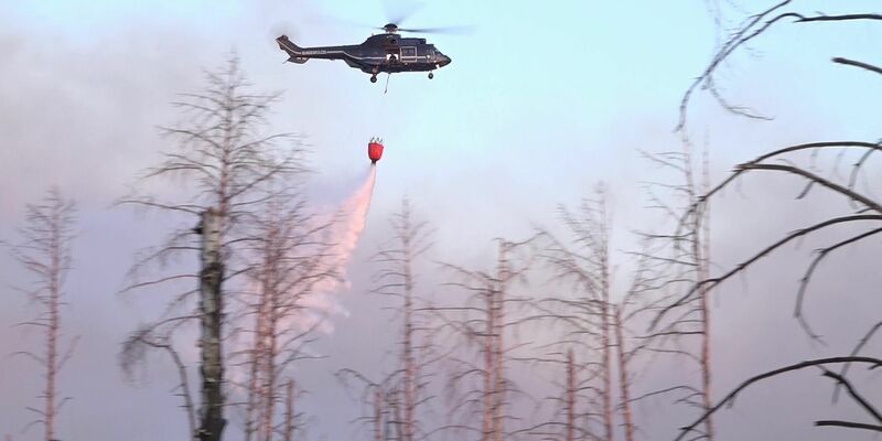 Ein Löschhubschrauber über dem Waldbrand in einem munitionsbelasteten Gebiet bei Jüterbog (Landkreis Teltow-Fläming). - Foto: Cevin Dettlaff/dpa