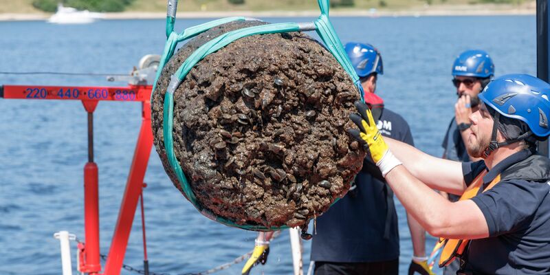 Ein Fass Branntkalk wird als Wrackteil eines Handelsschiffs der Hansezeit aus der Trave gehoben. - Foto: Markus Scholz/dpa