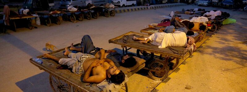 Arbeiter schlafen am Straßenrand an einem heißen Sommermorgen in Karatschi. - Foto: Fareed Khan/AP/dpa