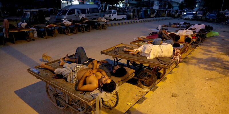 Verkäufer und Rikscha-Fahrer schlafen an einem heißen Sommermorgen in Karachi im Freien. - Foto: Fareed Khan/AP/dpa