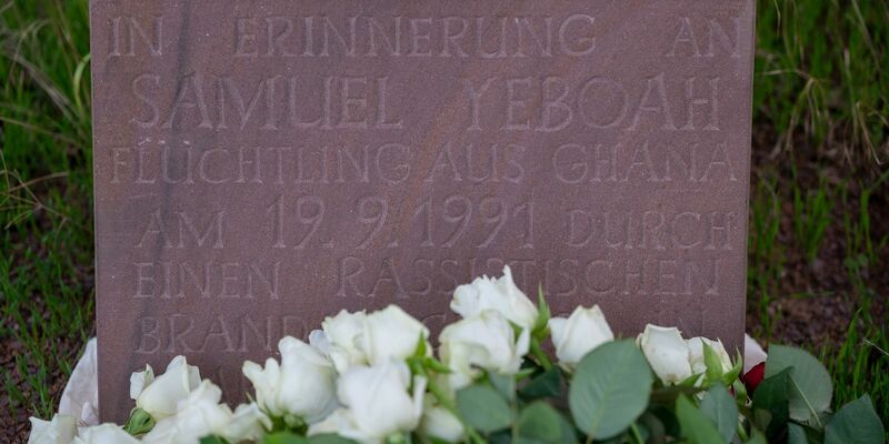 Teilnehmer der Gedenkkundgebung für den 1991 bei einem Brandanschlag getöteten ghanaischen Asylbewerber Samuel Yeboah haben an einem Gedenkstein Blumen abgelegt. - Foto: Harald Tittel/dpa