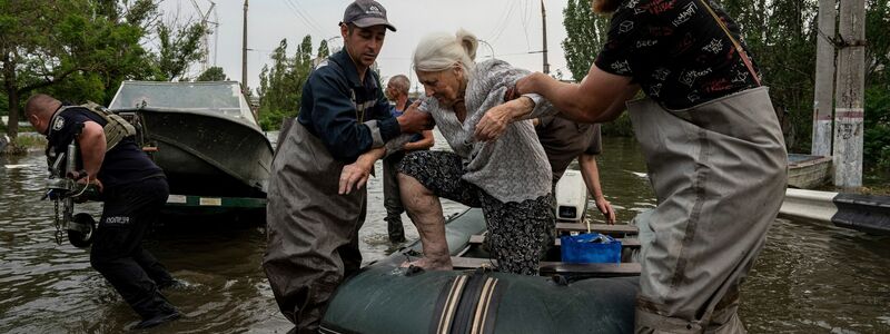 Rettungskräfte evakuieren eine ältere Frau aus einem überfluteten Viertel in Cherson. - Foto: Evgeniy Maloletka/AP