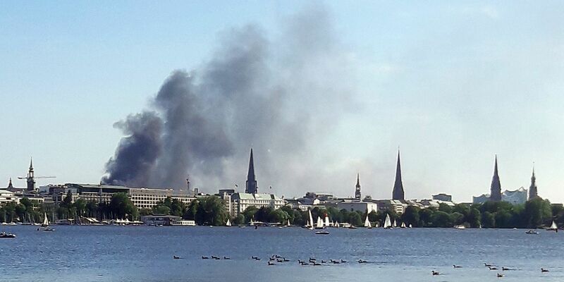 Eine Rauchwolke ist über der Alster in Hamburg zu sehen. Auf einem zehnstöckigen Haus in der Hamburger HafenCity ist es am Freitagnachmittag zu mehreren Explosionen gekommen. - Foto: Désirée Ballhausen/-/dpa