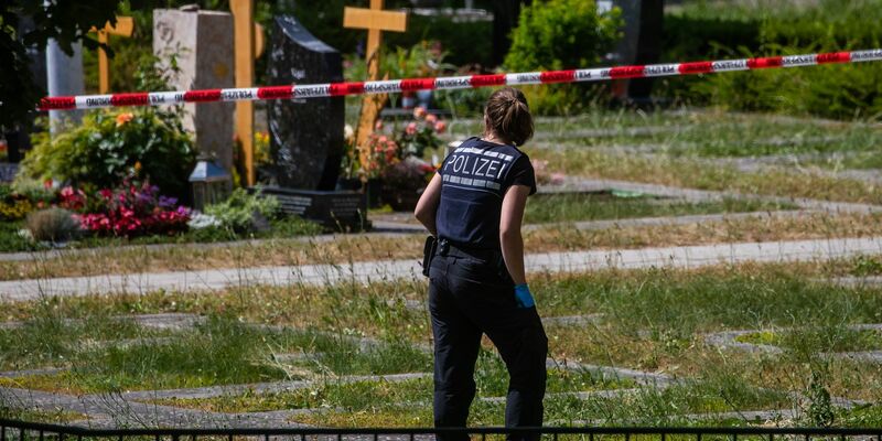 Eine Mitarbeiterin der Spurensicherung vermisst Spuren am Tatort auf einem Friedhof. - Foto: Christoph Schmidt/dpa