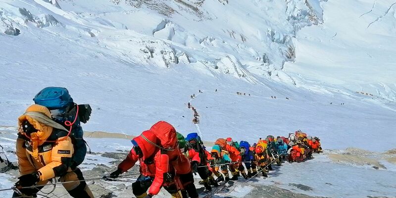 In einer langer Schlange gehen Bergsteiger auf einem Pfad knapp unterhalb von Lager vier auf dem Mount Everst. Bald ist ein Trecking-Gerät für jeden Pflicht. - Foto: Rizza Alee/AP/dpa