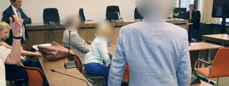 Die angeklagten Eltern sitzend und der angeklagte Arzt im Oberlandesgericht München. - Foto: Karl-Josef Hildenbrand/dpa