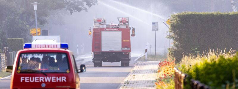 Feuerwehrfahrzeuge in der evakuierten Ortschaft Volzrade, durch die Rauch vom Waldbrand auf dem ehemaligen Truppenübungsplatz zieht. - Foto: Jens Büttner/dpa