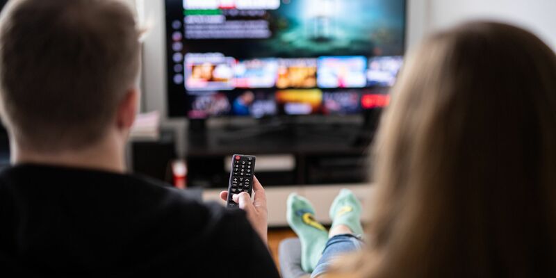 Ein junges Paar sitzt mit einer Fernbedienung vor einem Fernsehgerät. Das Fernsehen bleibt für Nachrichten für die meisten die wichtigste Quelle (Symbolbild). - Foto: Daniel Reinhardt/dpa