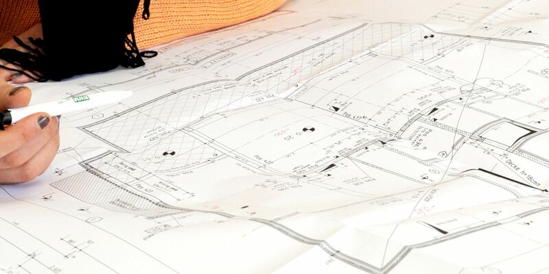 Eine Bauzeichnerin vor einem Bauplan. Die Bauindustrie fordert bessere digitale Lösungen für die Verwaltung. - Foto: Carsten Rehder/dpa